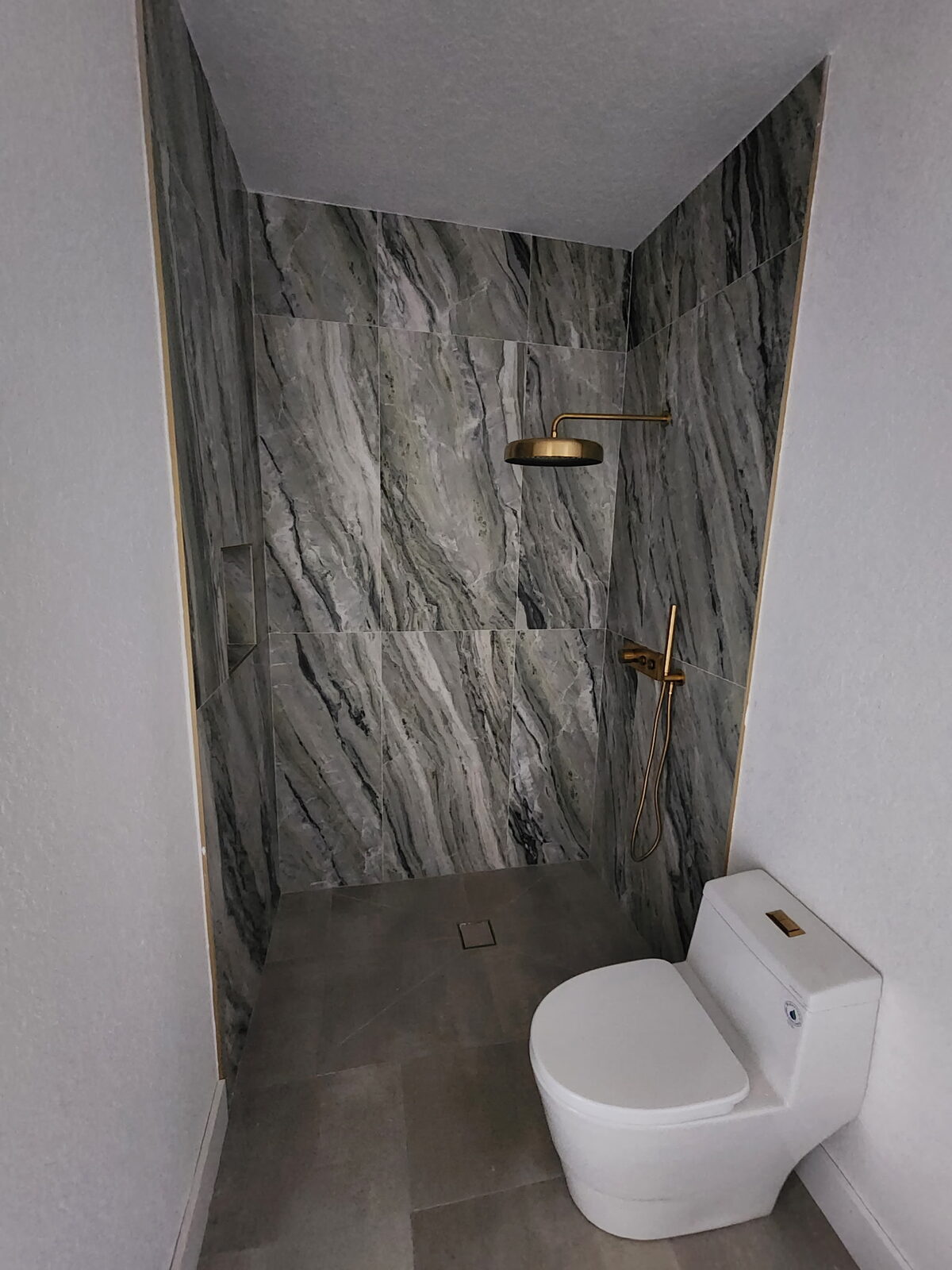 Marble-look tile shower with gold fixtures